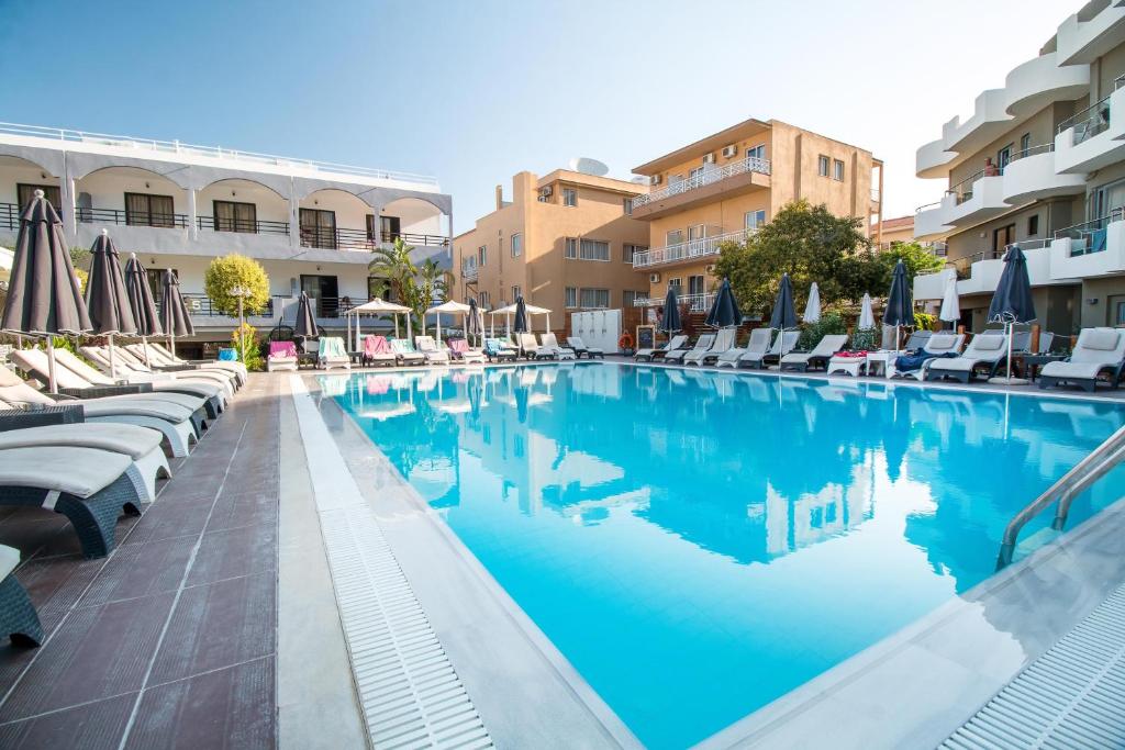 Sunny Days Hotel-Apartments baseins ar sauļošanās krēsliem un viesnīcas ēka