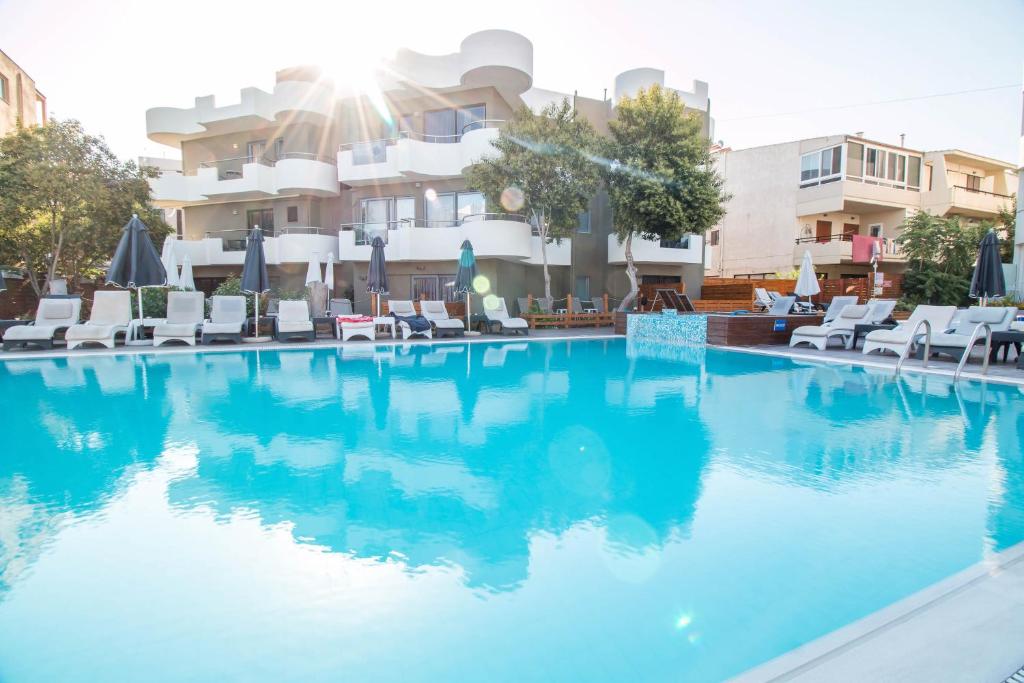 Sunny Days Hotel-Apartments baseins ar saules stariem un atpūtas krēsliem