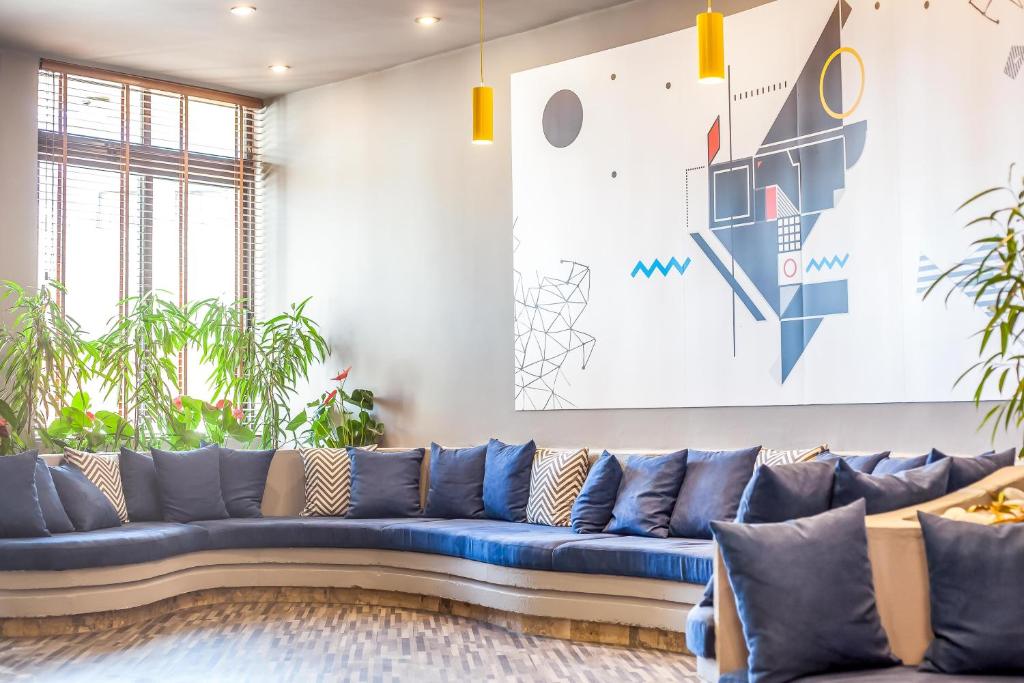 Moderns atpūtas stūrītis Sunny Days Hotel-Apartments ar zilu dīvānu un mākslas darbu uz sienas.