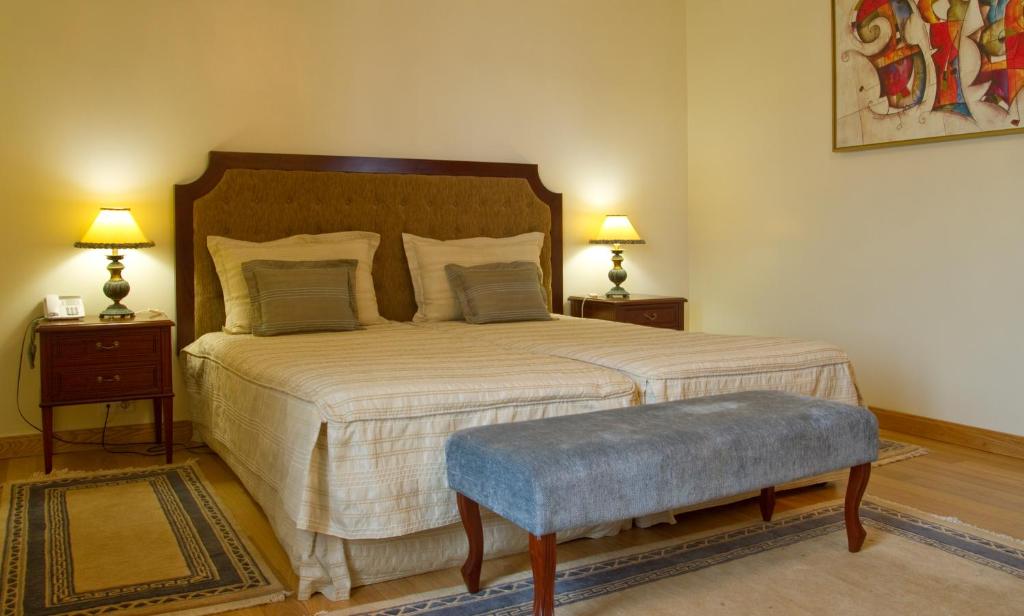 Mūsdienīgs guļamistabas interjers ar divguļamo gultu, blakus naktsgaldiņiem un lampām, kā arī dekoratīvu mākslas darbu uz sienas. Guļamistabā valda mierīga atmosfēra ar siltām krāsām.