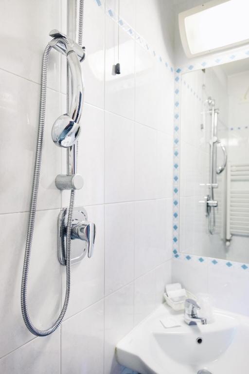 Mūsdienīgs dušas stūris ar hromētu dušas galvu un spoguli, kas atspoguļo minimalistisku vannas istabas dizainu.