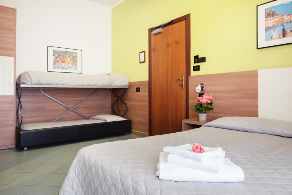 Mūsdienīgs viesnīcas numurs ar divguļamo gultu un diviem vienguļamajiem gultas matračiem. Telpā ir arī ziedu kompozīcija un mākslas darbs uz sienas.