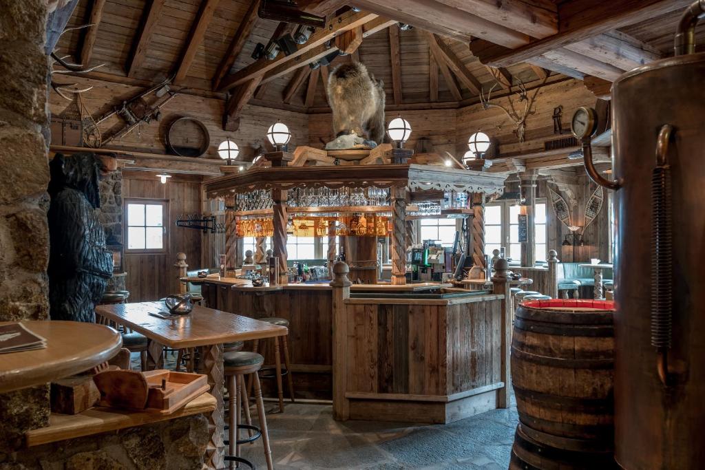Koka interjers ar bāru, kas dekorēts ar medību trofejām un tradicionālām meža tēmām, radot siltu un viesmīlīgu atmosfēru.