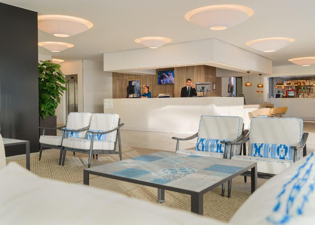 Mūsdienīgs viesnīcas reģistratūras interjers ar gaišu apgaismojumu, plašu bāru un viesmīlīgu apkalpošanu. Sēdvietas ar stilīgu dizainu un augošu augu akcentiem rada patīkamu atmosfēru.