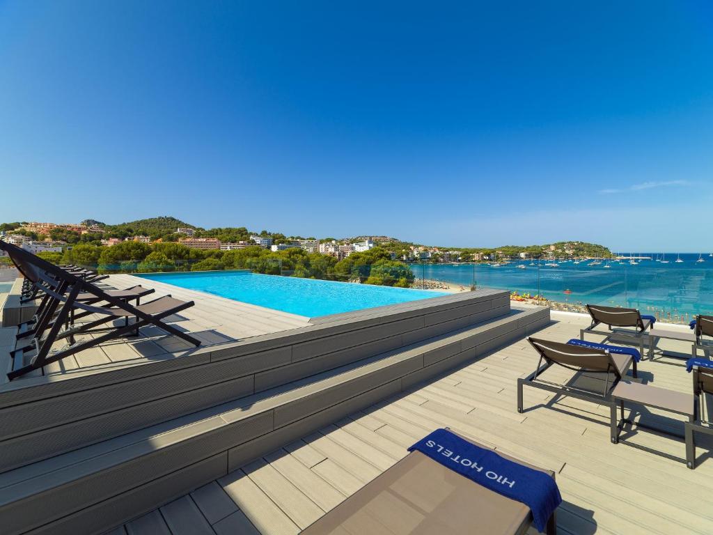 Brokastis ar skatu uz baseinu un jūru, kas atrodas viesnīcas terasē. Rāmā atmosfērā ir redzami sauļošanās krēsli un skaista ainava.