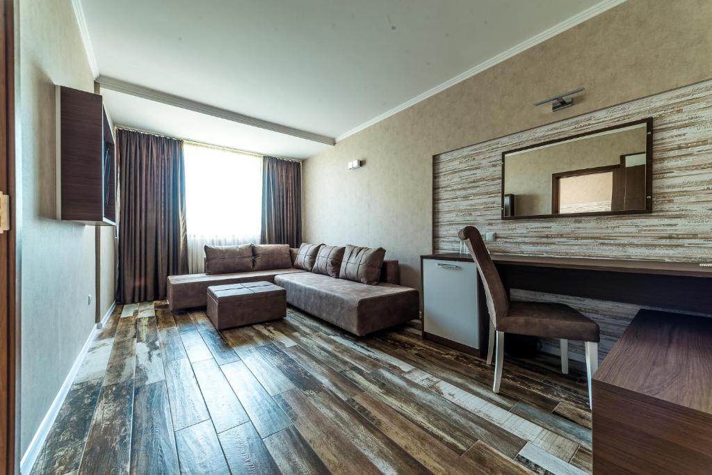 Mūsdienīgs viesnīcas numurs ar dīvānu, rakstāmgaldu un logu ar aizkariem, kas nodrošina dabisko apgaismojumu. Koka grīda piešķir siltumu un komfortu telpai.