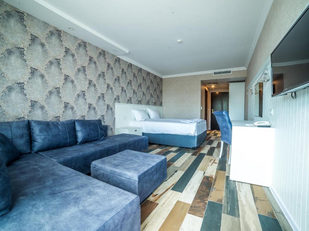 Mūsdienīgs viesnīcas numurs ar zilu dīvānu un daudzfunkcionālu mēbeļu komplektu, kā arī elegantu tapeti. Interjers ir gaišs un ērts, radot relaksējošu atmosfēru.