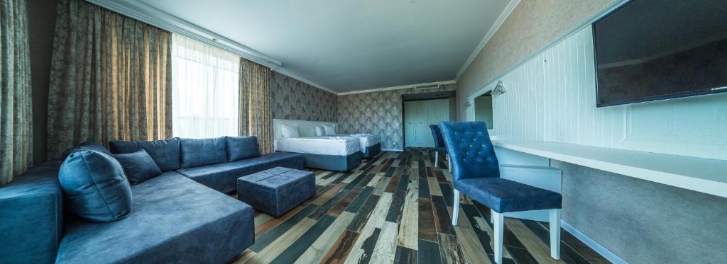 Mūsdienīga viesnīcas numura interjers ar komfortablu dīvānu, gultu un rakstāmgaldu. Gaismas toņos veidots noformējums un koka grīda rada mājīgu atmosfēru.