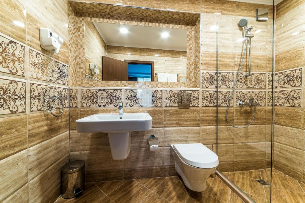 Mūsdienīga vannas istaba ar estētisku flīžu apdari un stikla dušas kabīni. Interjers ir gaišs un funkcionāls, ar elegantiem elementiem.