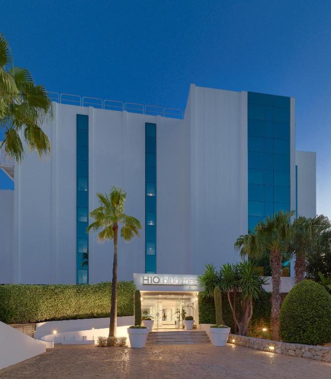 Mūsdienīgs viesnīcas ēkas fasāde ar stikla elementiem un zaļiem augiem priekšā, radot draudzīgu un pievilcīgu atmosfēru.