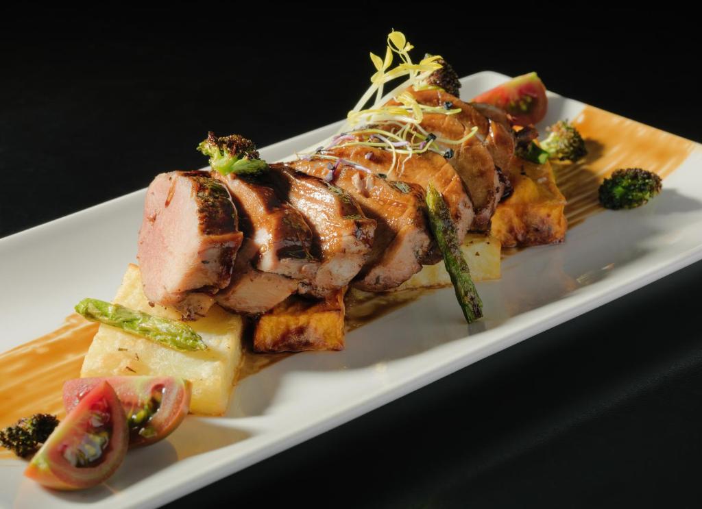 Svaigi pagatavota vistas gaļa ar dārzeņiem un garšīgu mērci, pasniegta uz elegantas baltas šķīvja.