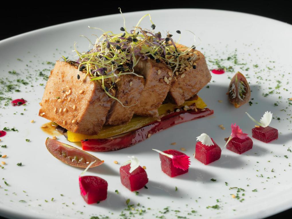 Gurķu un tomātu salāti ar ceptu tofu, dekorēti ar mikro zaļumiem un dārzeņu mērci. Pievienoti krāsaini dārzeņu kubi un zaļumi, kas piešķir ēdienam izsmalcinātu izskatu.