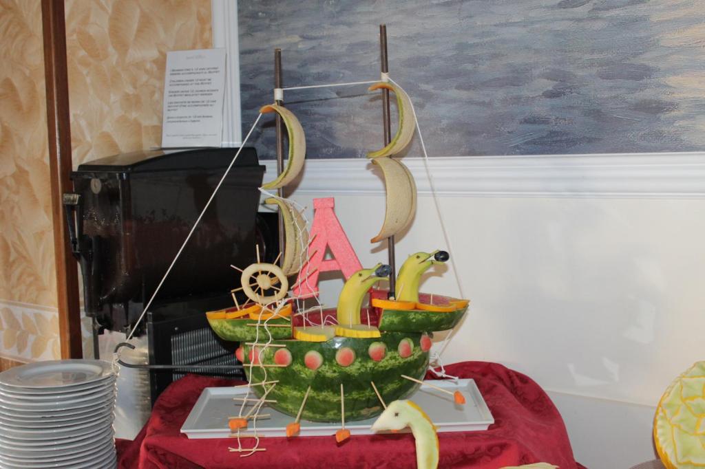 Augļu kuģa dekorācija, kas izveidota no arbūza, banāniem un citām augļu sastāvdaļām, rotā galdu. Kuģim ir buras, kas izgatavotas no banāniem, un tam ir radošs dizains ar krāsainām detaļām.