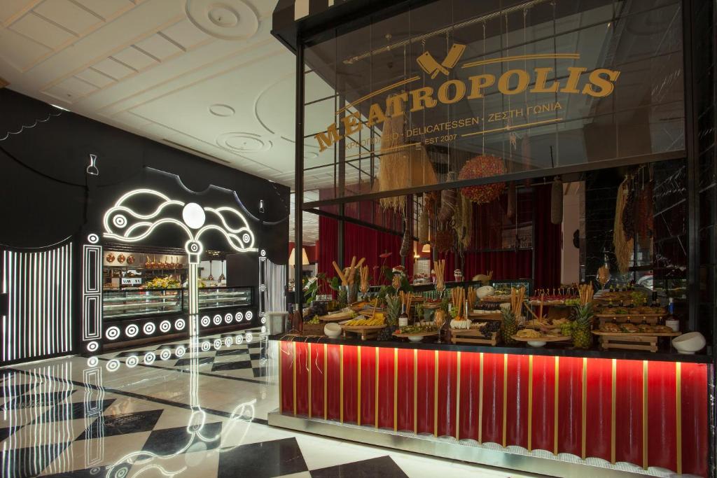 Elegants delikatešu veikals ar modernu interjeru, kas iekļauj melno un baltu krāsu kontrastus un stilīgas dekorācijas. Uz galda ir izkārtoti dažādi gardumi un svaigi produkti.