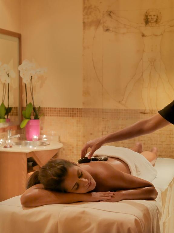 Masāžas procedūra relaksējošā vidē ar profesionālu masieri, kas izmanto masāžas rīku, lai nodrošinātu komfortu un atslābumu.