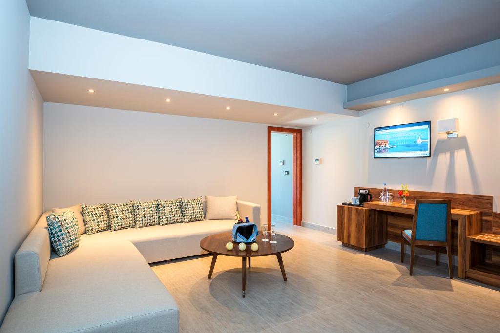 Mūsdienīgs viesnīcas numurs ar plašu dīvānu, galdu un televizoru. Gaismas krāsa un interjers rada ērtu un relaksējošu atmosfēru.