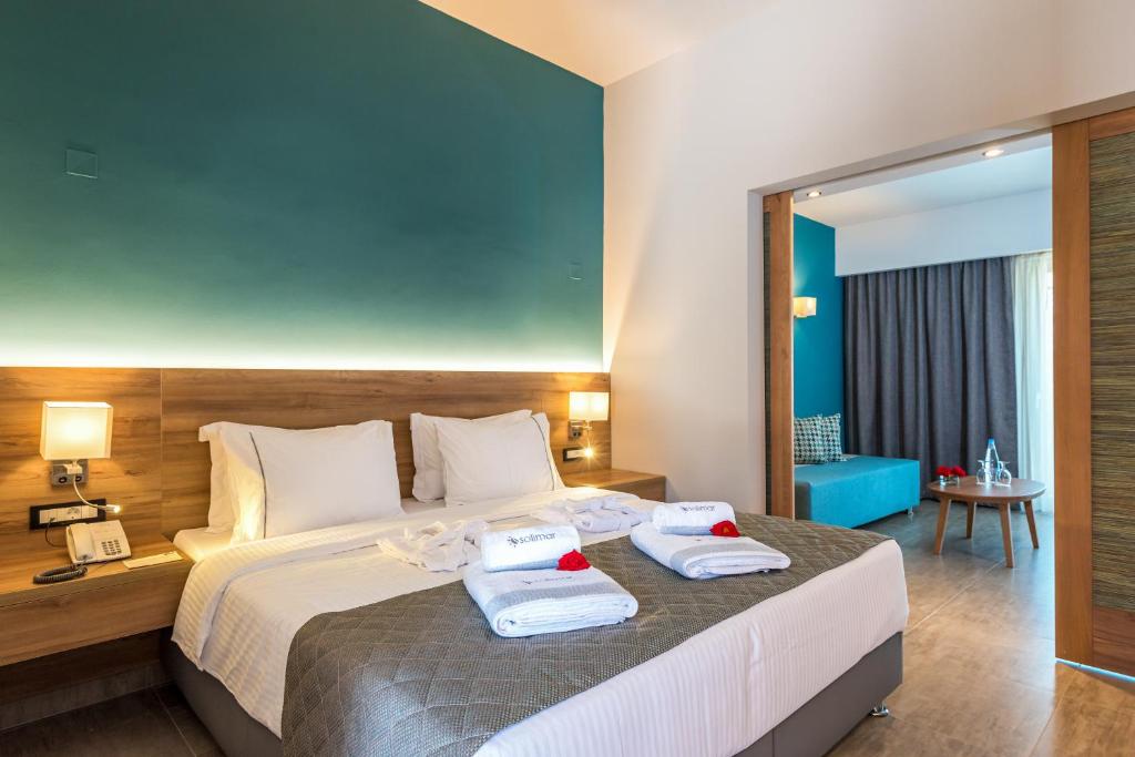 Mūsdienīgs viesnīcas numurs ar divguļamo gultu, gaišām gultasveļām un stilīgu dekoru, kas ietver zilu sienu un viesistabu ar dīvānu. Rūpīgi sakārtots, lai nodrošinātu komfortu un relaksāciju.