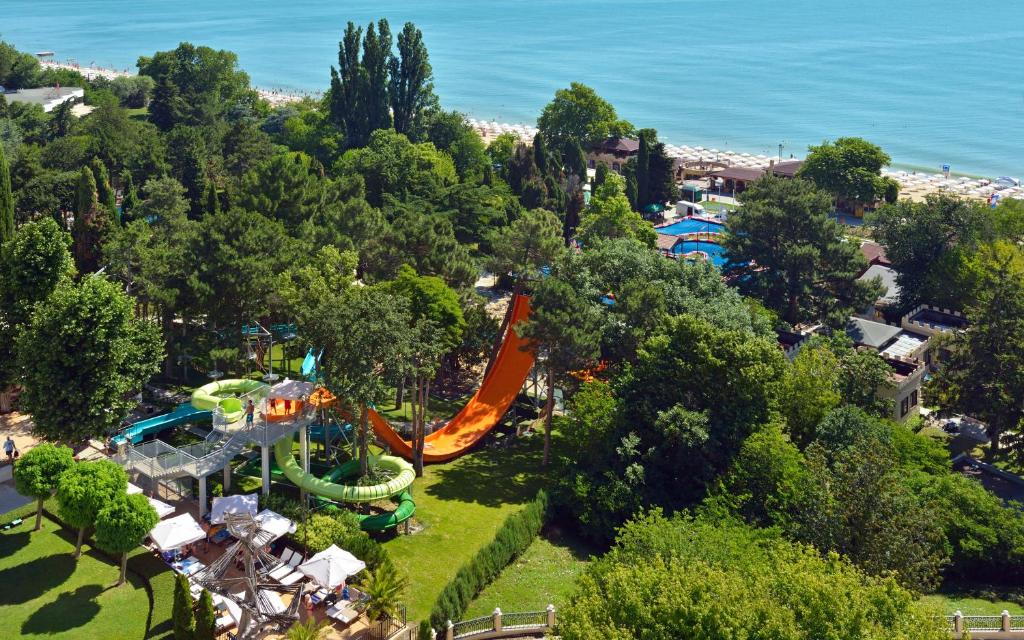 Ūdens atrakciju parks ar slidkalniņiem un zaļiem kokiem, blakus pludmalei un peldbaseinam. Skats uz jūru un apkārtējiem viesnīcu kompleksiem.