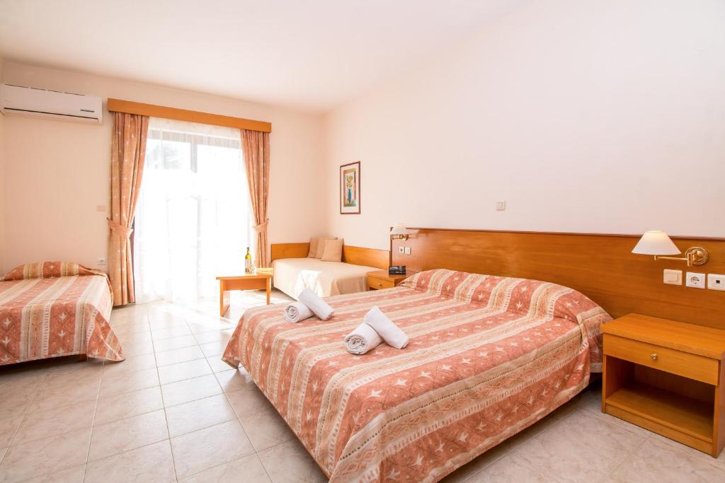 Gaisa kondicionēts viesnīcas numurs ar divām gultām un atsevišķu dīvānu, apgaismojums un koka mēbeles, ar skatu uz dārzu.