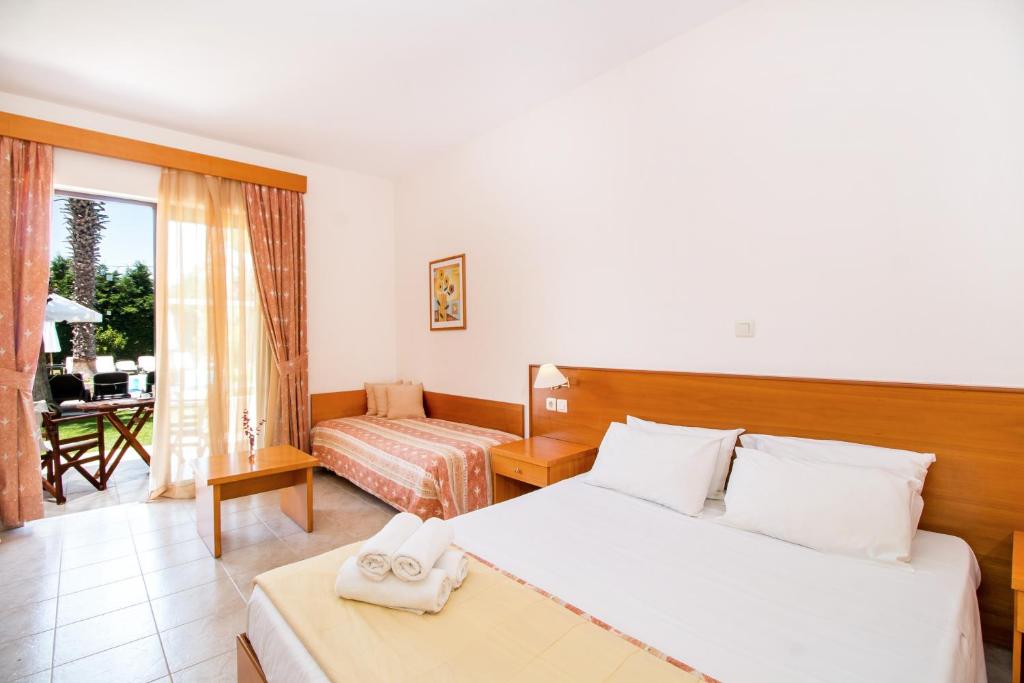 Mūsdienīga viesnīcas numura iekārtojums ar divām gultām, koka mēbelēm un lieliem logiem, caur kuriem redzams dārzs. Numurā ir arī dīvāns un dekoratīvas gleznas.