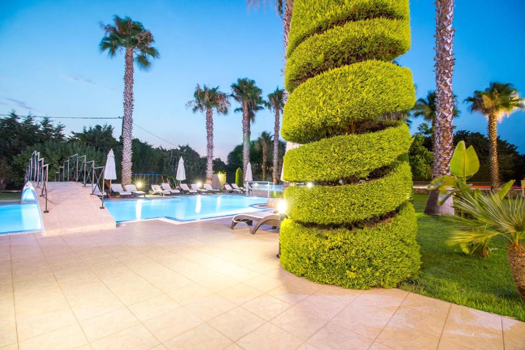 Vasaras atpūtas zona ar baseinu, palmām un stilīgu zaļo krūmu, kas veidots spirālē. Ideāla vieta relaksācijai un atpūtai.
