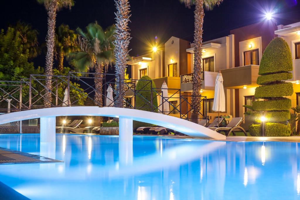 Baseins ar gaisotni un palmām, apgaismots naktī, ar balto tiltu un viesnīcas ēkām fonā. Ideāla vieta relaksācijai un brīvā laika pavadīšanai.