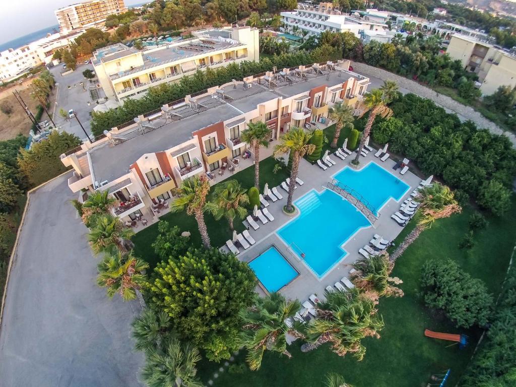 Viesnīcas komplekss ar diviem peldbaseiniem, palmas un sauļošanās krēsliem, atrodas gleznainā apkārtnē. Apvīts ar zaļumiem un tuvumā jūra.