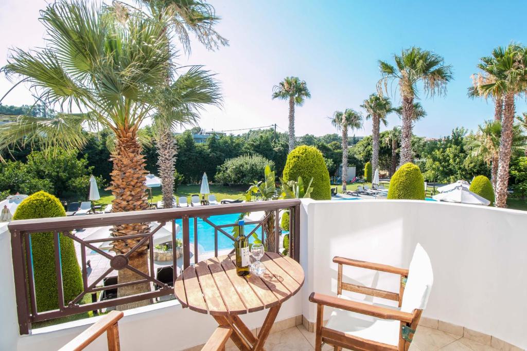 Balkons ar skatu uz baseinu un palmu dārzu, uz galda atrodas vīna pudele un glāzes. Ideāla vieta relaksācijai un atpūtai.