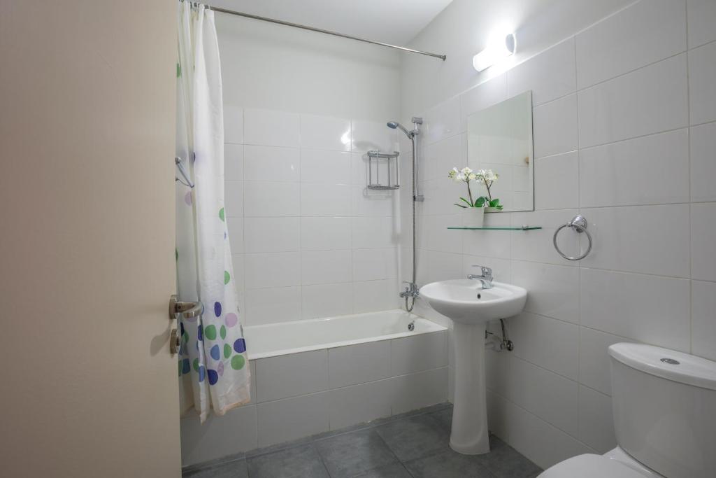 Mūsdienīga vannas istaba ar vannu, dušas aizkaru, izlietni un tualeti, apgaismojumu un dekoratīviem elementiem.