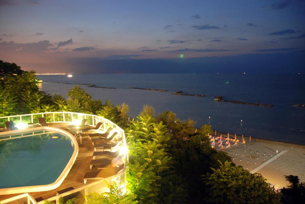 Eleganta nakts ainava ar baseinu, kas atrodas blakus pludmalei, un mierīgu jūras skatu. Zaļumi un apgaismojums piešķir atmosfēru relaksācijai.