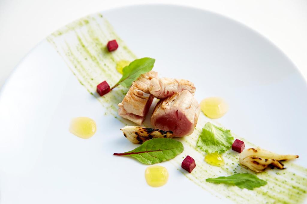 Gurmanu ēdiens ar grilētu gaļu, garnējumu no zaļumiem un dārzeņiem, dekorēts ar krāsainām mērcēm.