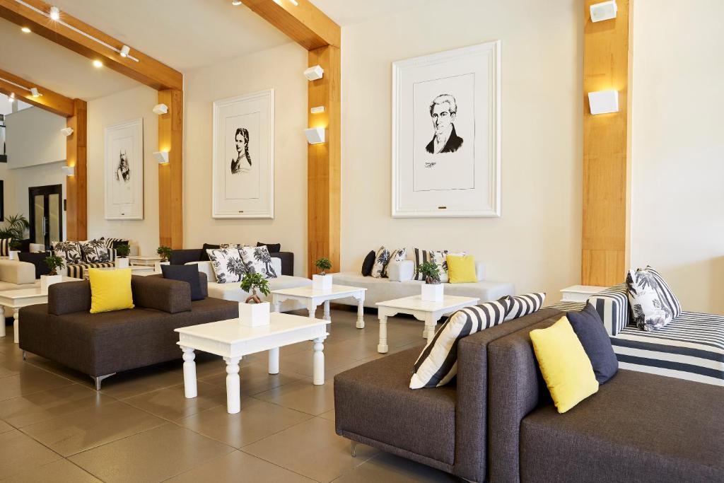 Mūsdienīgs viesnīcas vestibilis ar elegantiem dīvāniem un mākslas darbiem uz sienām. Interjers apvieno gaišus toņus ar melnbaltiem akcentiem, radot viesmīlīgu atmosfēru.