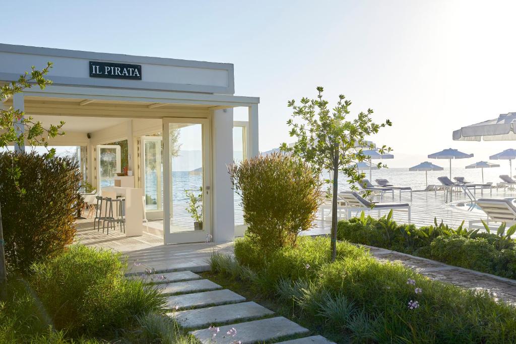 Restorāna "Il Pirata" āriene, kas atrodas pie jūras, ar zaļām ainavām un saulainu skatu uz pludmali.