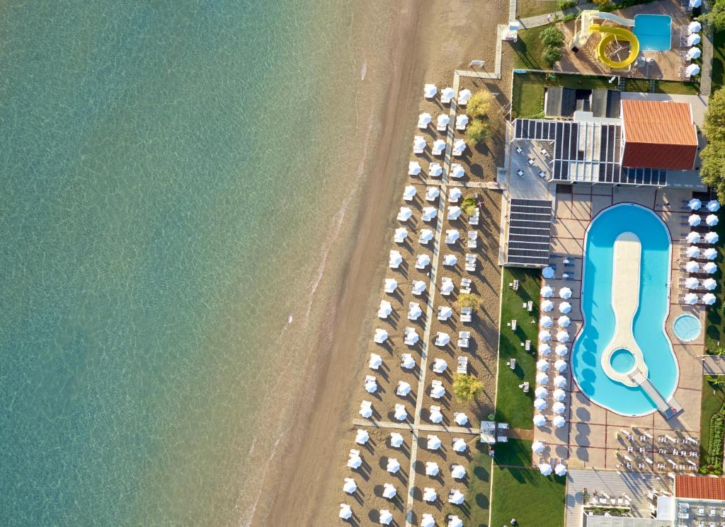 Peldbaseins un pludmales zona ar saulessargiem, redzama no augšas, blakus skaidrajam ūdenim. Ideāla atpūtas vieta pie jūras.