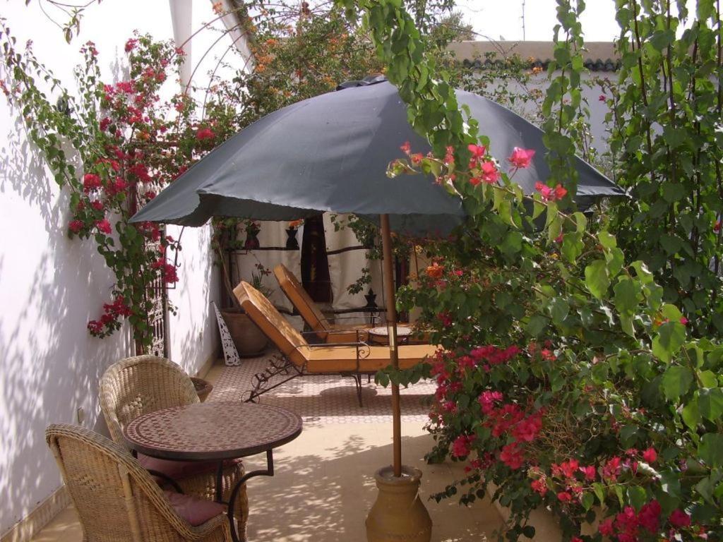 Skaista atpūtas zona ar sauļošanās krēsliem, galdu un lietussargu, ko ieskauj ziedoši augi un zaļumi. Ideāla vieta relaksācijai un dabas baudīšanai.