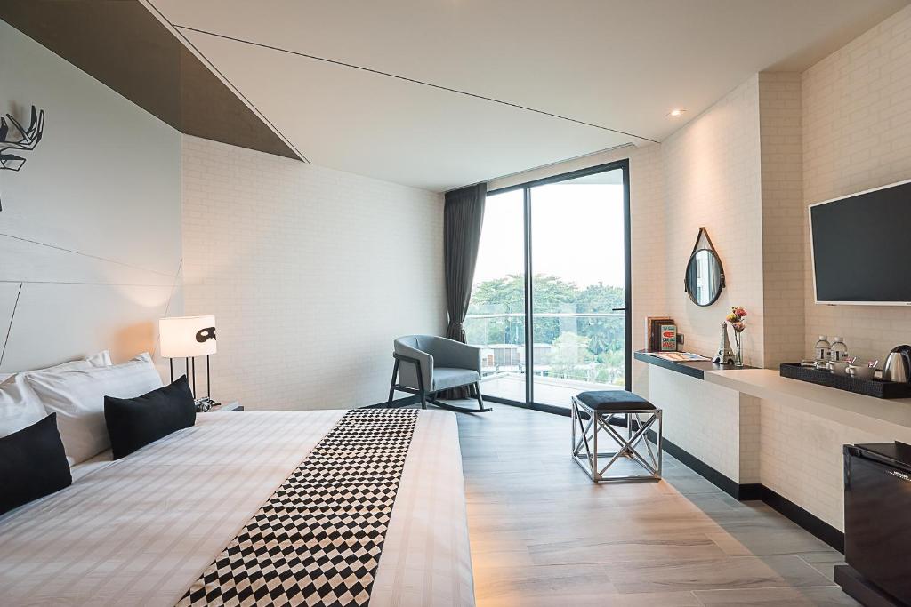 Mūsdienīgs viesnīcas numurs ar plašām logiem, kas nodrošina dabīgu apgaismojumu. Interjerā ir eleganta gultas veļa, moderna mēbeļu izvēle un minimālistisks dizains.