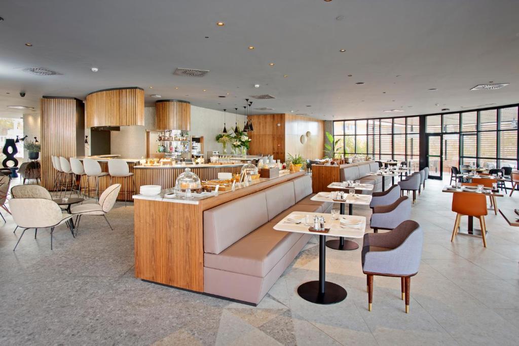 Mūsdienīgs restorāns ar koka akcentiem un elegantu interjeru, kurā ir stilīgas mēbeles un plašas logu vitrīnas. Ideāla vieta relaksācijai un maltītēm.