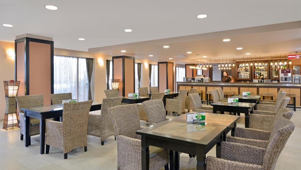 Moderns restorāns ar ērtām vītņu krēsliem un koka galdiem, kur apmeklētāji var baudīt dzērienus un uzkodas. Bāra zona ir redzama aizmugurē, radot patīkamu atmosfēru.