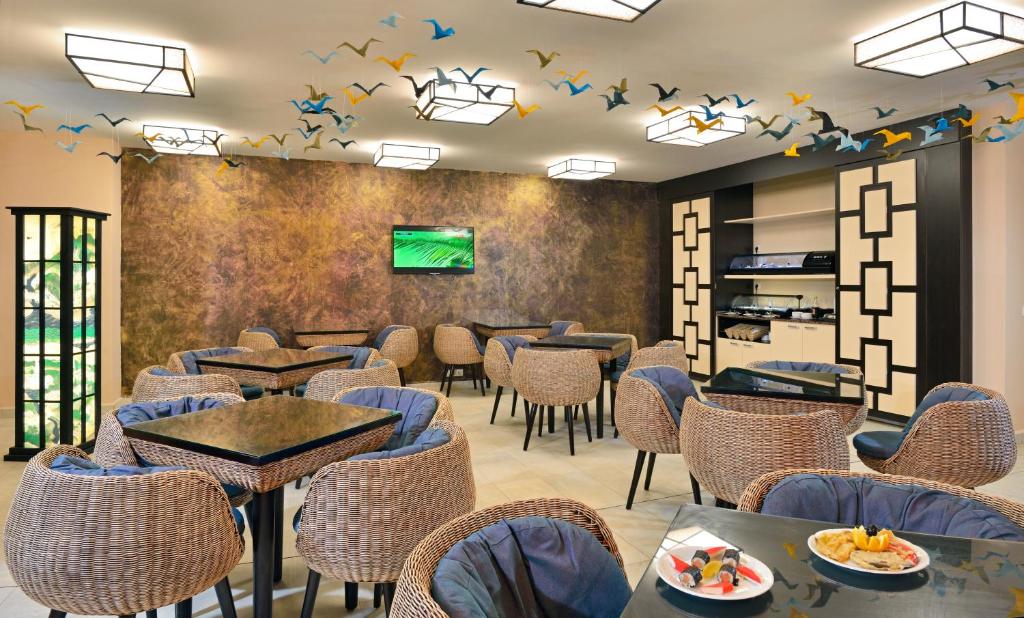 Mūsdienīgs kafejnīca ar komfortablu sēdvietu izkārtojumu, dekorēta ar krāsainām putnu ilustrācijām uz griestiem un ērtām rotangpalmas mēbelēm. Galdi ir aptīti ar tumšām virsmām un zilu audumu.