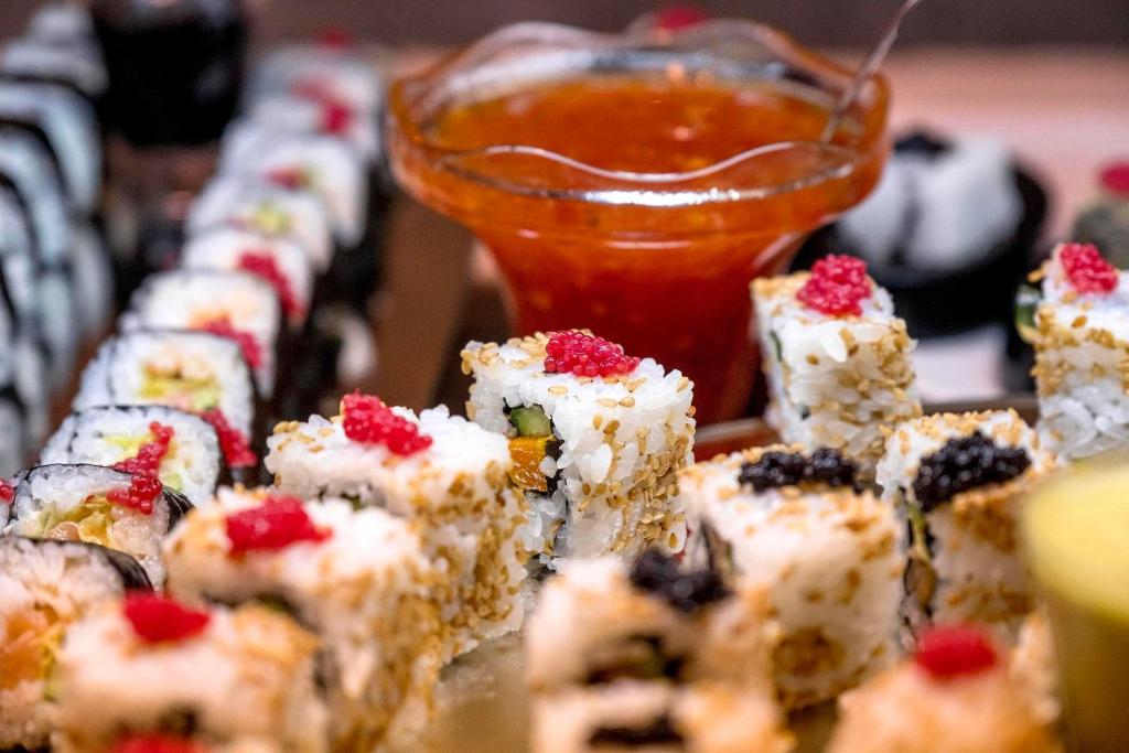 Svaigu sushi šķēlītes ar sezama sēklām un garnējumu, kopā ar garšīgu mērci. Ideāls ēdiens japāņu virtuvei.