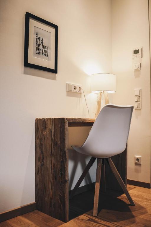 Mūsdienīgs rakstāmgalds ar koka apdari un stilīgu krēslu, apgaismojums un plakāts ar citātu par smaidu.