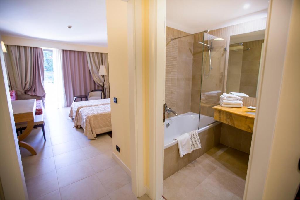 Mūsdienīgs viesnīcas numurs ar vannas istabu, kurā ir vanna un moderns aprīkojums. Telpa ir gaiša un ērta, radot patīkamu atmosfēru atpūtai.