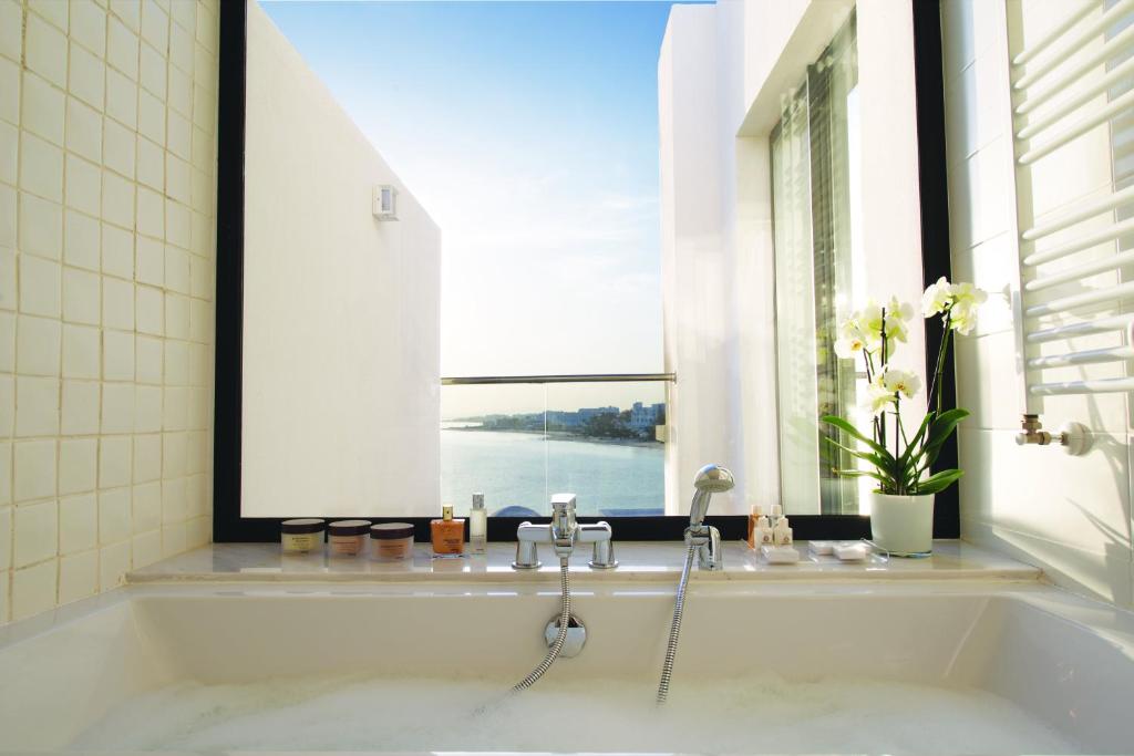 Luksusa vannistaba ar skatu uz ūdeni un ziediem. Eleganti vannas piederumi un gaiša, moderna interjers.