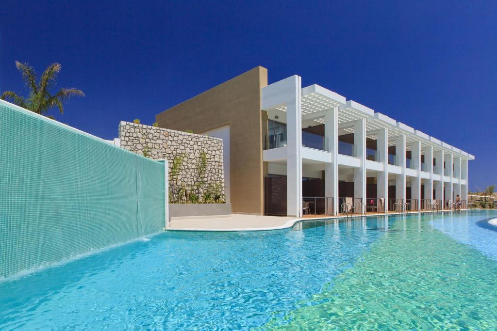 Princess Andriana Resort & Spa baseins ar mūsdienīgu arhitektūru un skaidru zilu ūdeni.