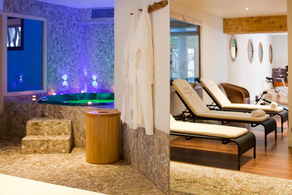 Mūsdienīgs spa interjers ar relaksējošu atmosfēru, kurā redzams džakuzi un atpūtas krēsli. Sienas dekorētas ar dabīgiem akmeņiem, radot mierīgu vidi.