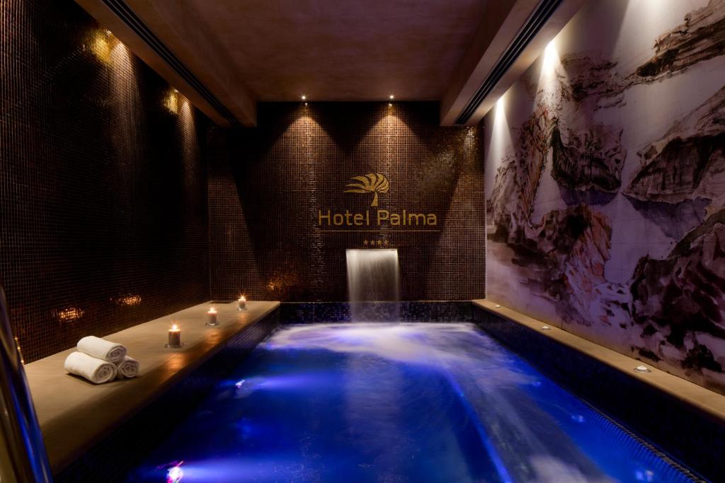Mūsdienīgs spa ar relaksējošu atmosfēru, kurā redzama zila ūdens plūsma un elegantas apgaismojuma detaļas. Griestos redzams viesnīcas "Hotel Palma" logo.