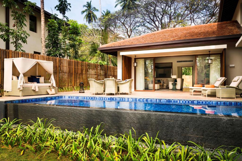 Mūsdienīga villa ar privātu baseinu un ērtu atpūtas zonu dārzā. Apkārt aug zaļa zāle un palmas, radot mierīgu un relaksējošu atmosfēru.