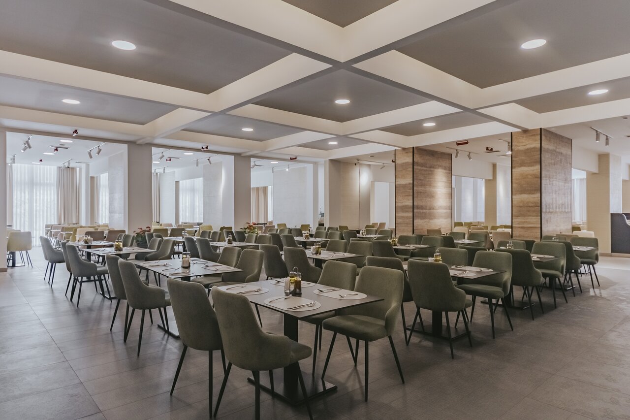 Hotel Tara modernā ēdamistaba ar zaļiem krēsliem un galdiem.
