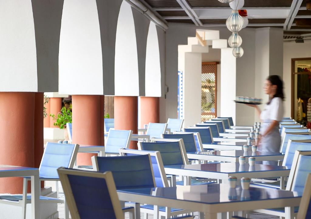 Restorāns Knossos Royal ar gaišām mēbelēm un apkalpojošo personālu.