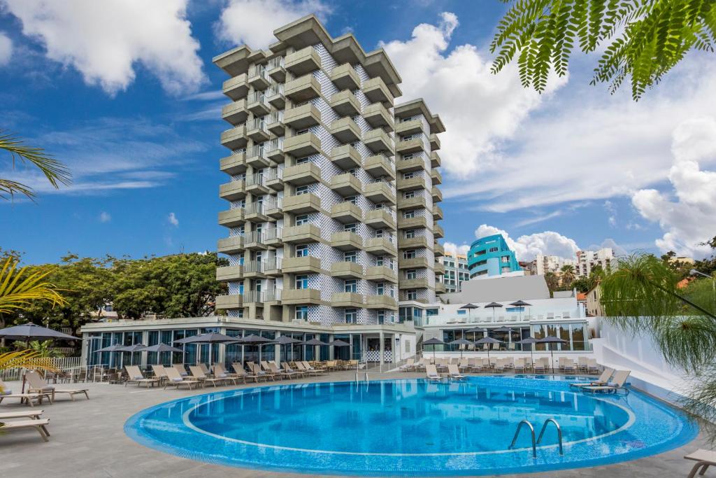 Mūsdienīgs viesnīcas komplekss ar baseinu un sauļošanās zonu, ieskauts zaļumiem un zilām debesīm. Ideāla vieta relaksācijai un atpūtai.